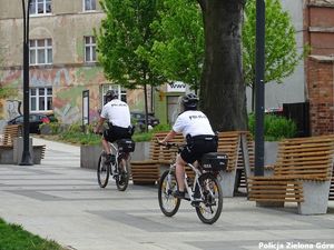 Policjanci jadący rowerami na terenie deptaku.