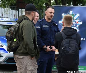 Policjant rozmawiający z dwójką cywili.