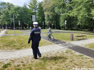 Policjantka wydziału ruchu drogowego nadzoruje rowerzystów poruszających się po miasteczku ruchu drogowego.