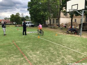 Policjantka nadzoruje rowerzystę poruszającego się po placu rowerowym.