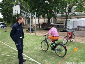 Policjantka nadzoruje rowerzystę poruszającego się po placu rowerowym.