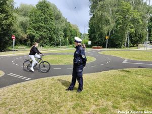 Policjantka wydziału ruchu drogowego nadzoruje przejazd rowerzystki po skrzyżowaniu o ruchu okrężnym.