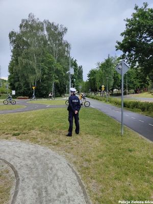 Policjantka wydziału ruchu drogowego nadzoruje rowerzystów poruszających się po miasteczku ruchu drogowego.