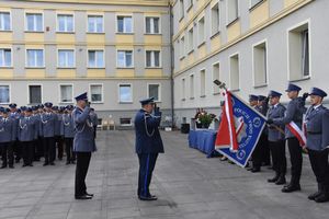 Grupa policjantów mniejsza z nich trzyma sztandar.