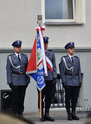 trójka policjantów stojąca ze sztandarem.