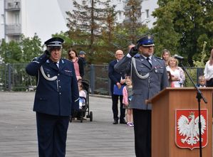 Dwóch policjantów, jeden z nich wygłasza przemowę.