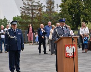 Policjanci stojący na baczność na tle cywili.