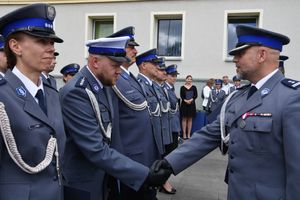 Policjant ściska dłoń innego policjanta stojącego w szeregu.