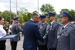 Policjant ściska dłoń prezydenta miasta.