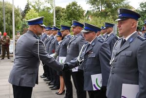 Policjant ściska dłoń innego policjanta w szeregu.