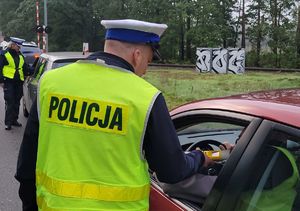 Policjant ruchu drogowego bada trzeźwość kierowcy pojazdu.