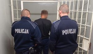 Dwójka policjantów odprowadza podejrzanego do celi.