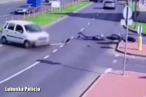 Leżący na jezdni kierowca motocykla a obok osobówka z którą się zderzył.
