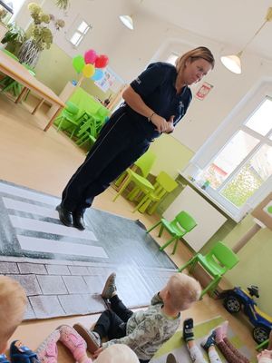 Policjantka stoi przed grupą słuchających ją dzieci.