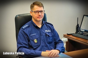 Policjant siedzący za biurkiem.