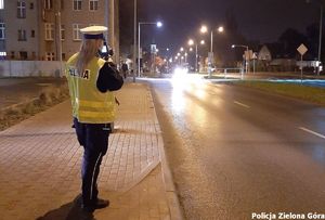 Policjantka mierzy prędkość nadjeżdżającego samochodu.