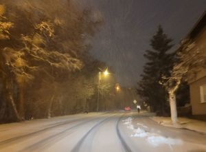 Zdjęcie zaśnieżonej ulicy w nocy.