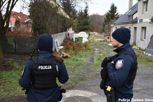 Dwójka policjantów obok zniszczonego domu.