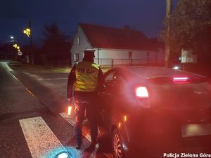 Policjant badający trzeźwość kierowcy samochodu osobowego.