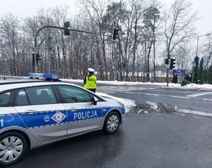 Policjanci obok radiowozu policyjnego mierzący prędkość samochodów.