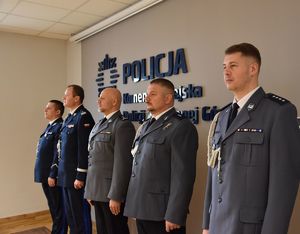 Pięciu policjantów a w tle napis Policja Komenda Miejska Policji.