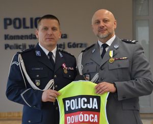 Komendant oraz podinspektor trzymający plastron z napisem &quot;Policja Dowódca&quot;.