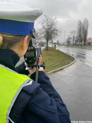 Policjantka mierząca prędkość nadjeżdżającego samochodu.