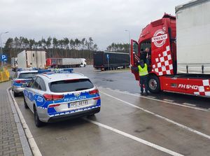 Policjant ruchu drogowego bada trzeźwość kierowcy tira.