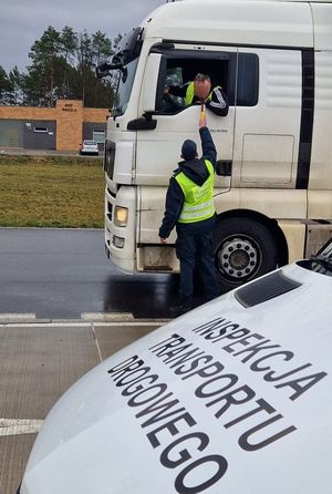 Policjant z ruchu drogowego badający trzeźwość kierowcy pojazdu wielotonowego.