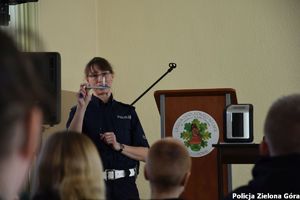 Policjantka promuje zawód policjanta absolwentom szkoły średniej w Sulechowie.