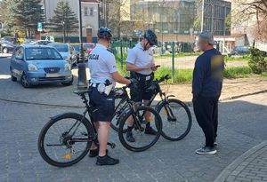 Dwóch policjantów na rowerach kontroluje mężczyznę
