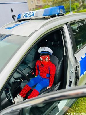 Chłopiec w stroju Spider-Mana siedzący w radiowozie.