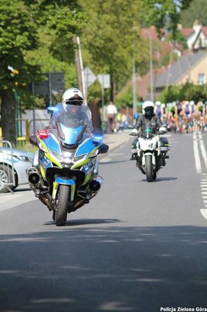 Policjanci na motocyklach jadący przez drogę.