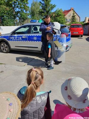 Policjant zakłada jednemu z dzieci hełm i kamizelkę