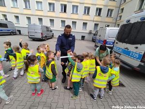 Policjant rozdaje opaski odblaskowa dzieciom