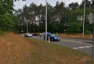 Policjantka sprawdza trzeźwość kierowcy samochodu koloru niebieskiego.