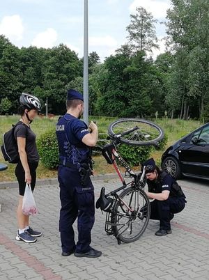 Policjant i policjantka sprawdzają legalność pochodzenia jednośladu. Obok funkcjonariuszy stoi właścicielka roweru.