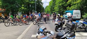 Rajd rowerowy. Porządku pilnują policjanci na motorach policyjnych. W oddali stoi samochód służbowy Inspekcji Transportu Drogowego.