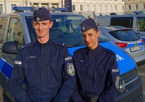 Policjant i policjantka na tle policyjnego radiowozu.