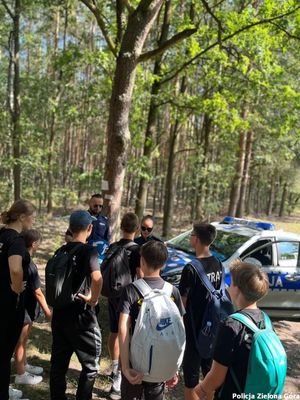 Zdjęcie ukazujące dzieci słuchające wypowiedzi funkcjonariusza policji.