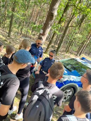 Zdjęcie ukazujące dzieci słuchające wypowiedzi funkcjonariusza policji.