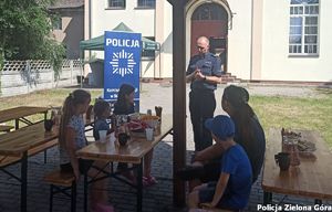 Zdjęcie ukazujące dzieci słuchające wypowiedzi funkcjonariusza policji.