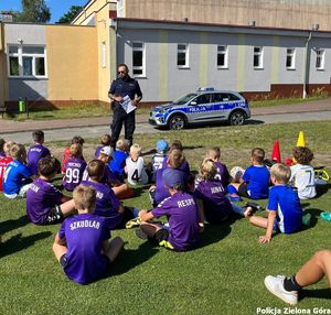 Zdjęcie ukazujące dzieci słuchające wypowiedzi funkcjonariusza policji.