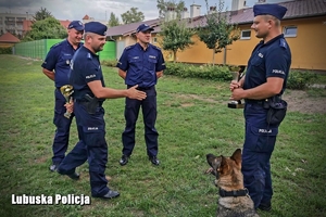 Policjant wręcza nagrodę innemu funkcjonariuszowi.