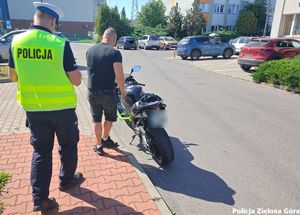 Policjant po zakończonej legitymacji kierowcy motocykla.