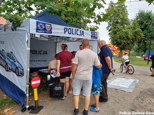 Stragan policyjny z funkcjonariuszem w środku z grupą dorosłych ludzi.