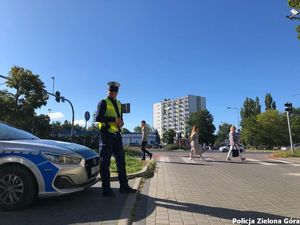 Policjant stojący obok radiowozu.