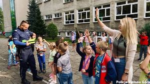 Policjant wraz z grupą dzieci oraz ich wychowawcą.