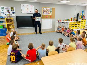 Funkcjonariusz policji edukuje dzieci na temat bezpiecznego powrotu ze szkoły.