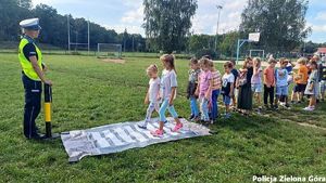 Policjantka uczy dzieci na temat bezpieczeństwa na drodze na świeżym powietrzu.